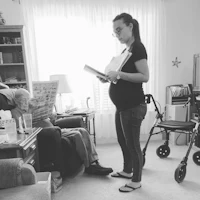 a pregnant woman reading a book in a living room